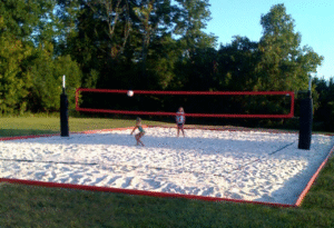 Outdoor sand volleyball court with a red net and two players in action on a bright day