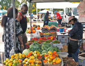 Fresh produce and vibrant community atmosphere at an outdoor farmers market stall 