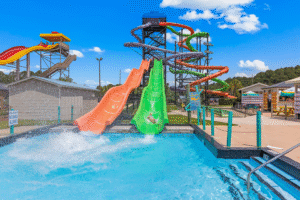 Colorful water slides at a lively water park pool under clear skies 
